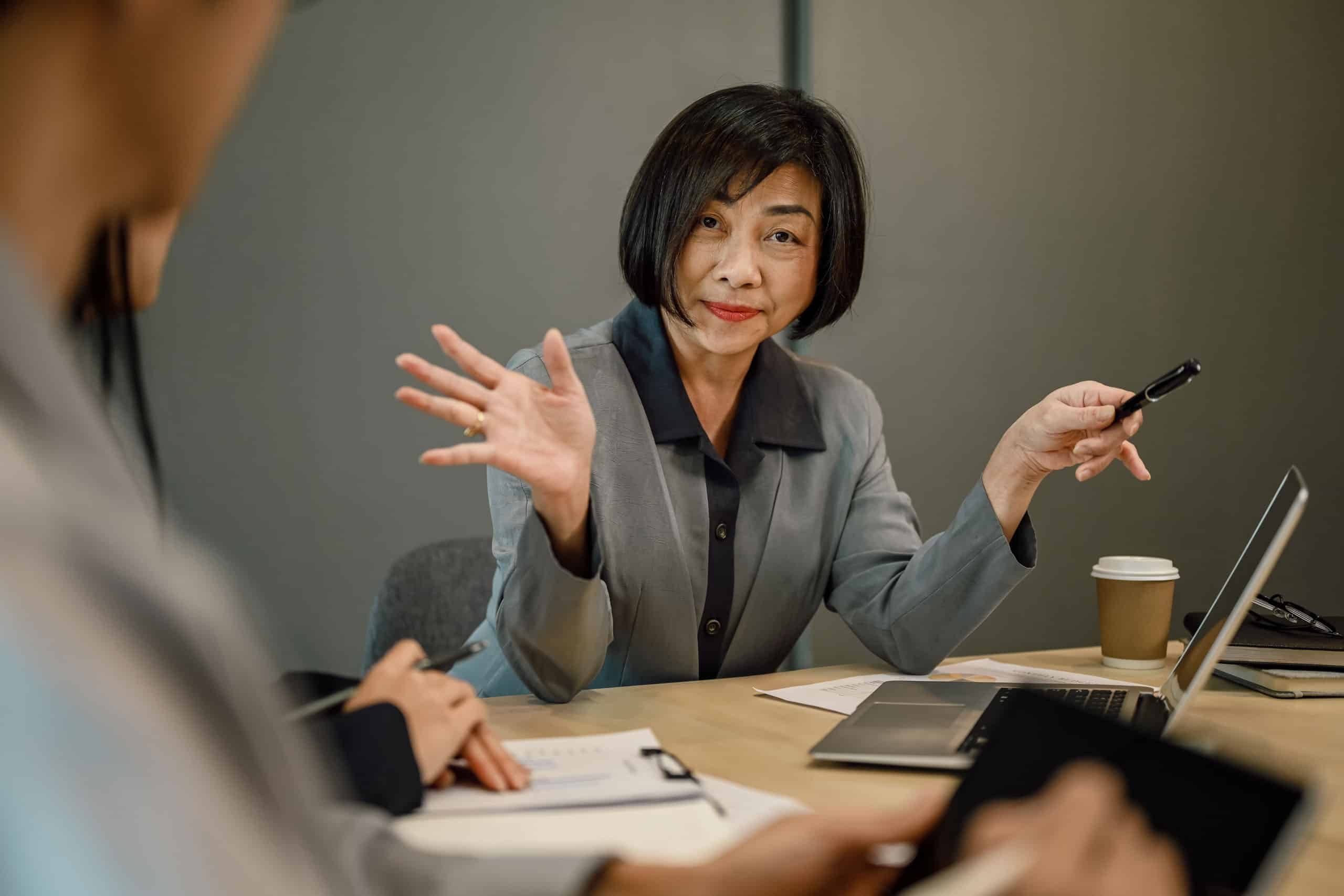 Selbstbewusste, mittelalte Geschäftsfrau in formeller Kleidung überzeugt einen Kunden während eines Meetings